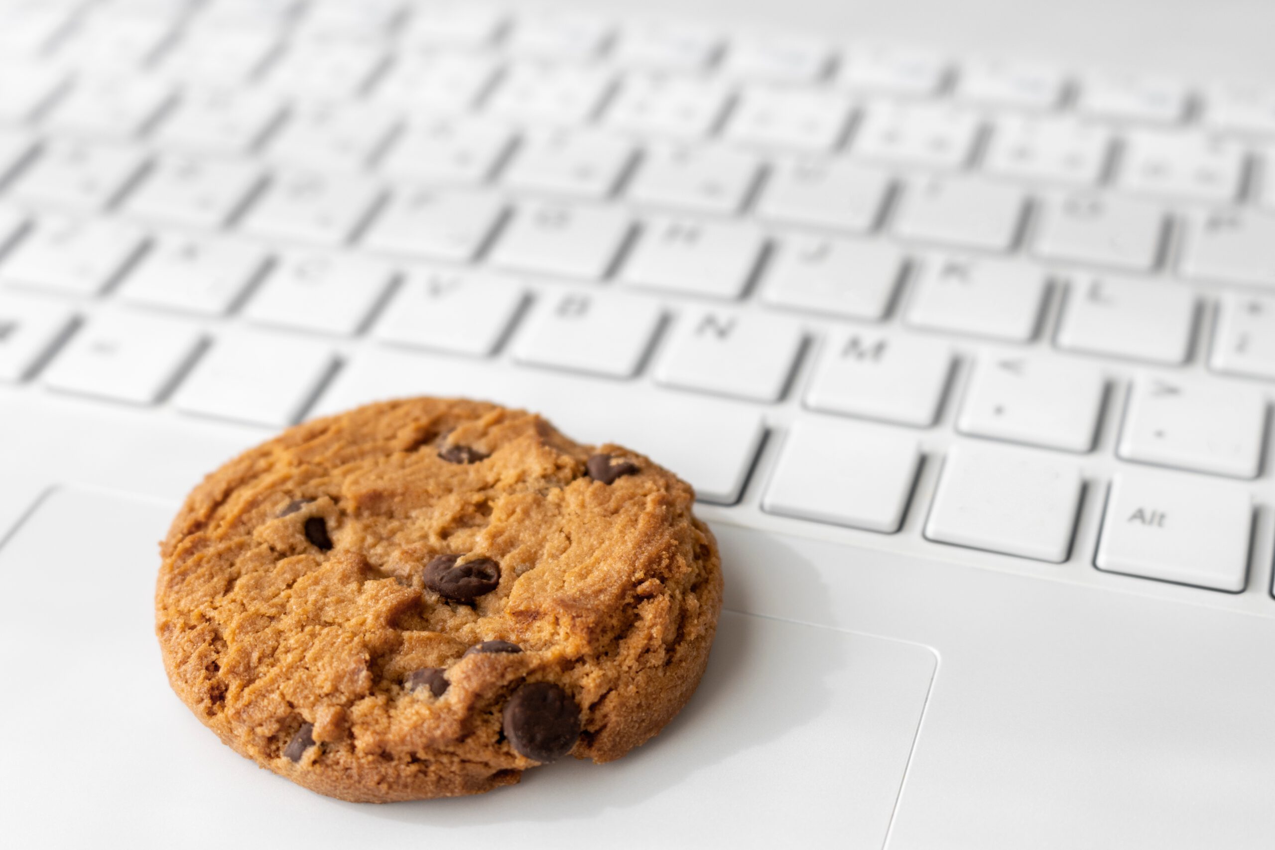 Ein Schoko-Cookie liegt auf einer weißen Computer Tastatur.