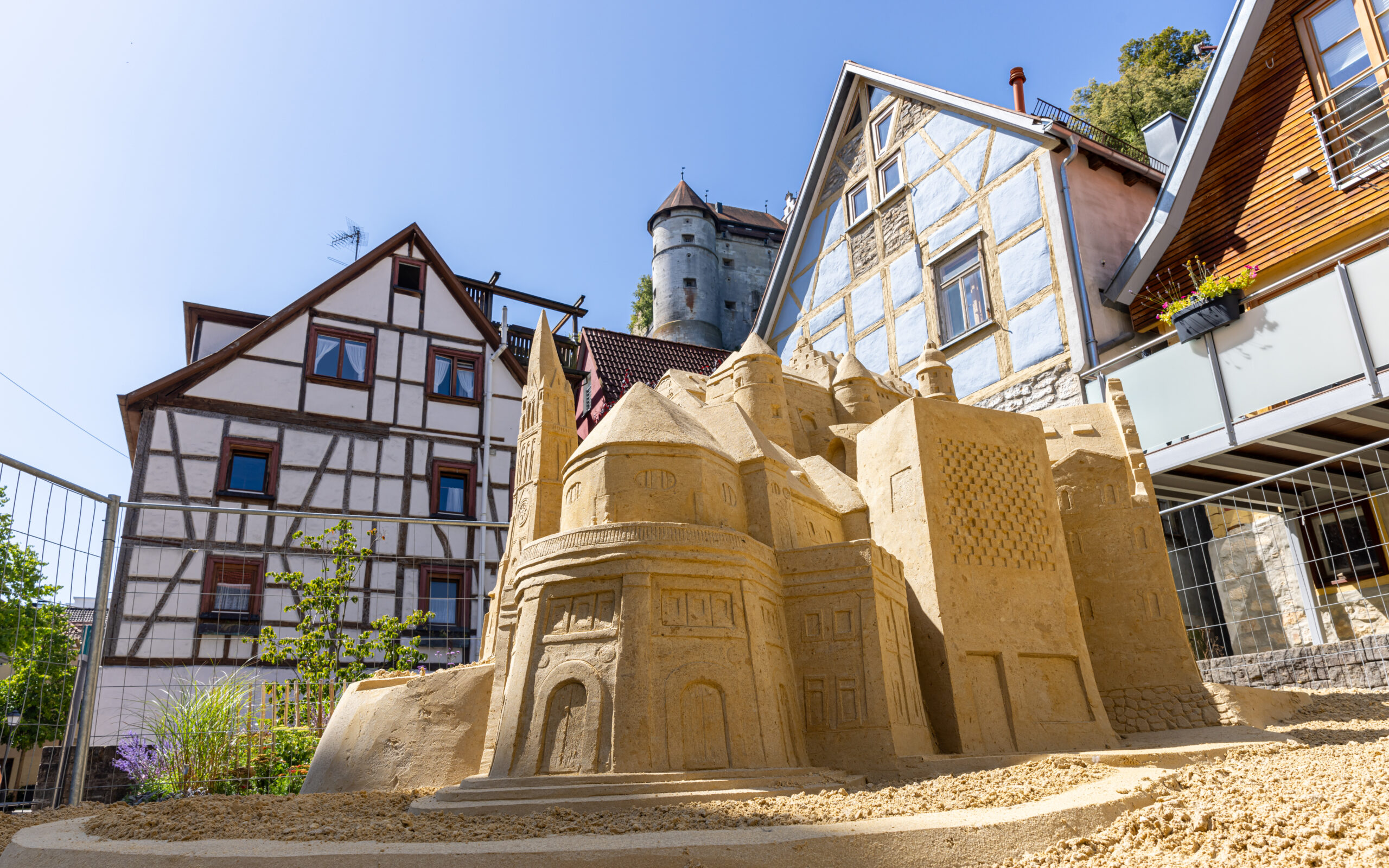 Fotografie einer Sandskulptur des Schloss Hellenstein vor Fachwerkhäusern und dem Schloss Hellenstein