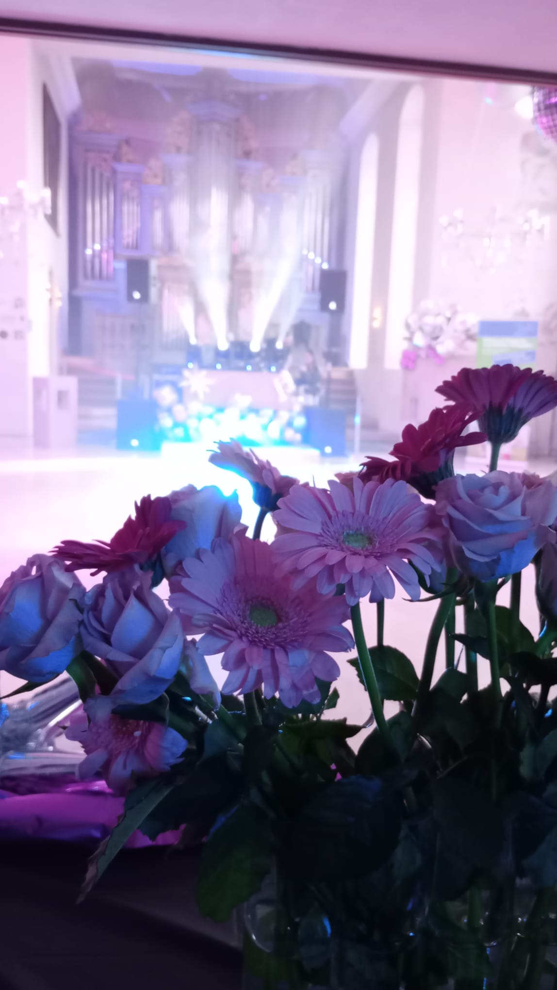 Blumen im Vordergrung, im Hintergrund sieht man den dekorierten Raum der Michealskirche für das Event Partynacht ab acht.